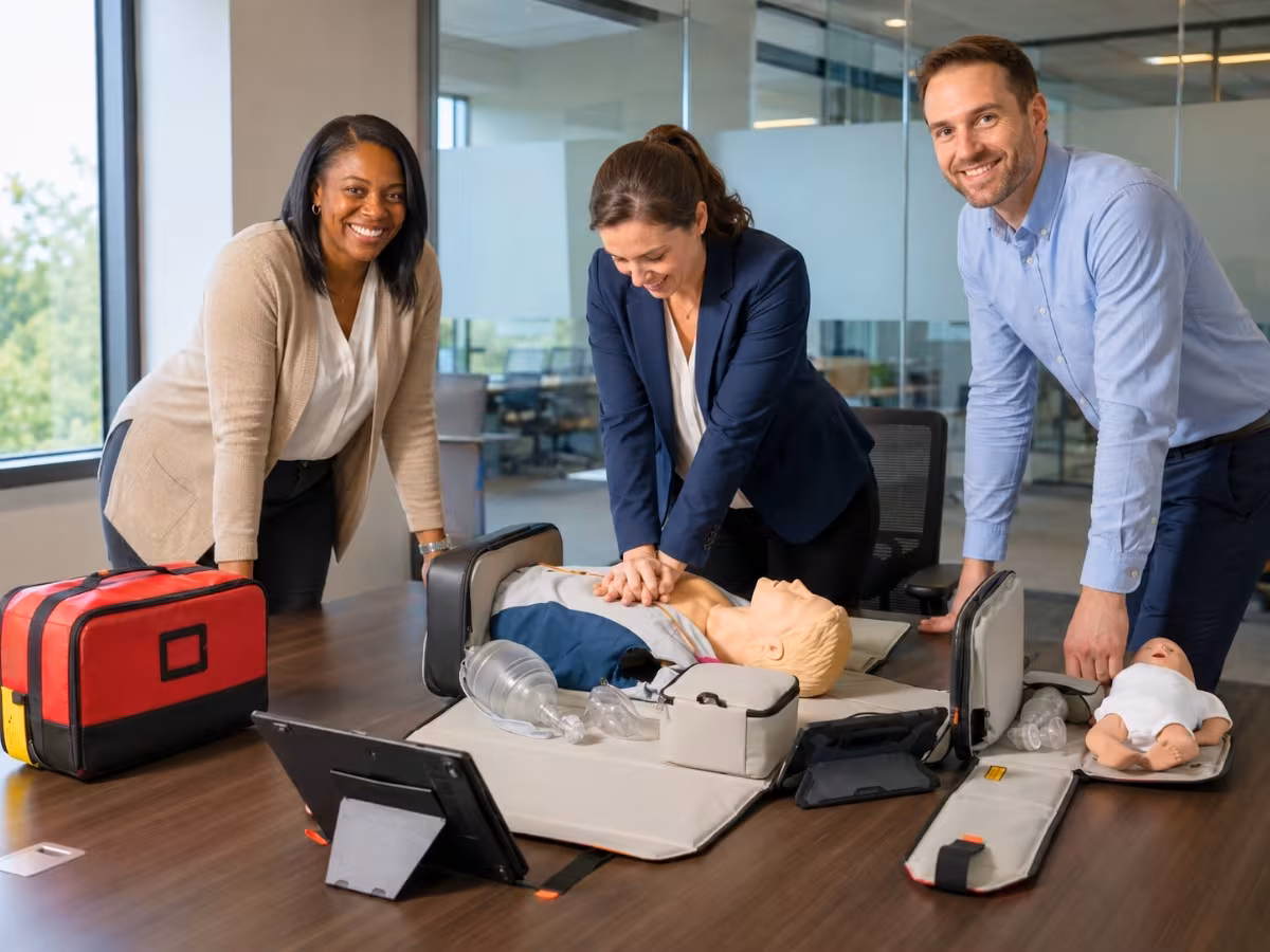 Employees practicing chest compressions on a manikin in an office conference room
